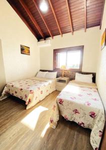 1 dormitorio con 2 camas y ventana en Duplex Accorsi Gramado, COM 2 SUITES, en Gramado