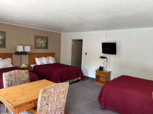 a hotel room with two beds and a table and chairs at Redwood Arms Motel in Paonia