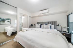 ein weißes Schlafzimmer mit einem großen Bett und einem Spiegel in der Unterkunft Luxury Heights on Flinders in Adelaide