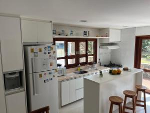 a kitchen with white cabinets and a white refrigerator at Suites Amma Noronha in Fernando de Noronha