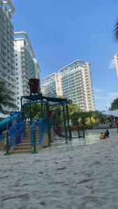 a playground on a beach with tall buildings at S&N Azure Staycation in Manila