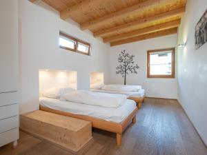 two beds in a room with wooden floors and windows at Kirchberg am Bach in Kirchberg in Tirol