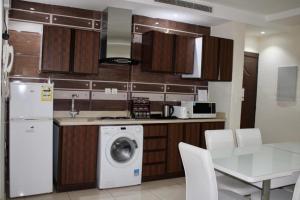 a kitchen with a washing machine and a table with chairs at Shouel Inn Furnished Apartments in Makkah