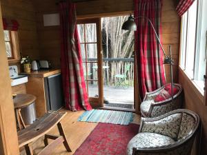 sala de estar con 2 sillas y puerta corredera de cristal en Kanuka Retreat en Akaroa