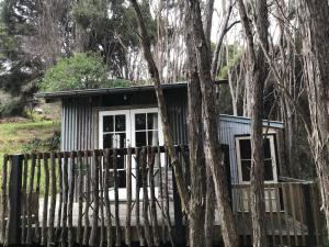 a tiny house in the woods behind a fence at Kanuka Retreat in Akaroa