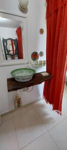 a bathroom with a sink and a mirror and red curtains at Recanto da Poesia in Campo Grande