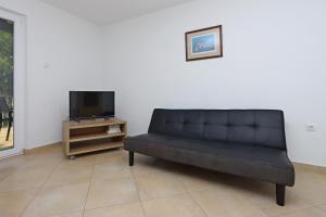 a black couch in a living room with a tv at Apartments by the sea Omisalj, Krk - 5298 in Omišalj