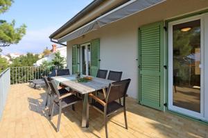a patio with a wooden table and chairs on a deck at Apartments by the sea Omisalj, Krk - 5298 in Omišalj