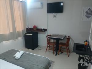 Habitación con cama, mesa y TV. en SUITES VISTA MAR AZUL, en Saquarema