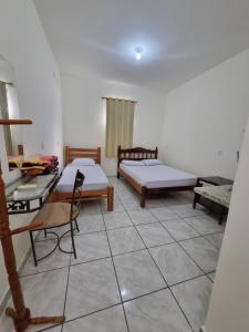 a room with two beds and a table and chairs at Pousada Renascer in Cuiabá