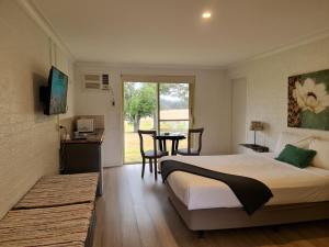 a bedroom with a bed and a table and a window at Vacy Hunter Valley Lodge in Vacy