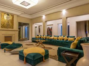 Palatial Oasis with Pool- VacayX - MARRAKECH في مراكش: غرفة معيشة مع أريكة خضراء ومدفأة