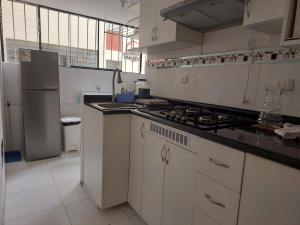 a white kitchen with a stove and a refrigerator at Mandalas Cusco in Cusco