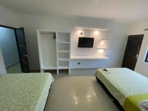 a bedroom with two beds and a flat screen tv at Hotel Los Paisas in Mitú