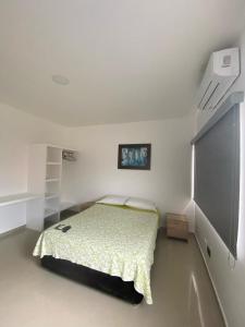 a white bedroom with a bed and a tv at Hotel Los Paisas in Mitú