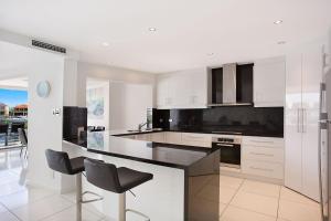 a kitchen with white cabinets and black appliances at A Perfect Stay - Casa Grande On The Water in Gold Coast