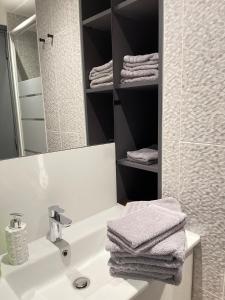 ein Badezimmer mit Waschbecken, Spiegel und Handtüchern in der Unterkunft DG Apartment - Le Relais du Lac, proche Disneyland Paris in Lognes + 19 Fotos