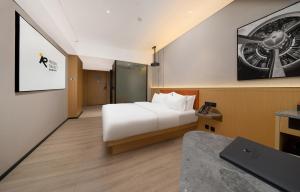 花都にあるGuangzhou Baiyun Airport Rezen Select Hotelの白いベッドとプロジェクターが備わるホテルルームです。