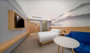 a hotel room with a bed and a blue couch at Guangzhou Baiyun Airport COCO Hotel in Huadu