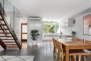 cocina y comedor con mesa de madera y sillas en A Perfect Stay - 1 James Cook Apartments, en Byron Bay