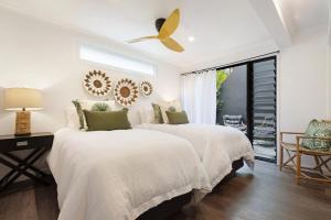 two beds in a white bedroom with a ceiling fan at A Perfect Stay - A Top Spot in Byron Bay