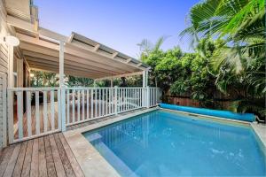 a swimming pool next to a house with a fence at A Perfect Stay - A Summer Cottage in Byron Bay