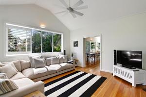 a living room with a couch and a flat screen tv at A Perfect Stay - A Summer Cottage in Byron Bay