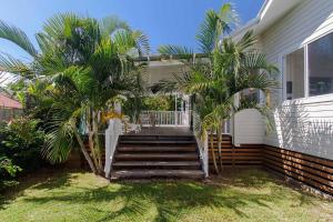 a house with palm trees in front of it at A Perfect Stay - A Summer Cottage in Byron Bay