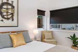 a bedroom with a bed and a chair and two windows at A Perfect Stay - Aditi in Byron Bay