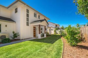 a large white house with a grass yard at A Perfect Stay - Amity at Seadrift in Byron Bay