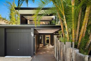 a house with a black garage and palm trees at A Perfect Stay - Arya in Byron Bay