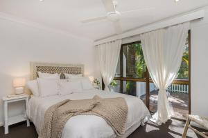 a white bedroom with a bed and a window at A Perfect Stay - Banjos on Paterson in Byron Bay