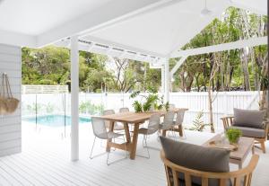 a white pergola on a deck with a table and chairs at Barrel & Branch in Byron Bay