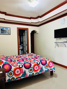 盧納將軍城的住宿－Siargao By Grace Suites，一间卧室配有一张带五颜六色棉被的床