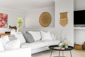 a white living room with a white couch and a table at A Perfect Stay - Boardroom at Wategos in Byron Bay