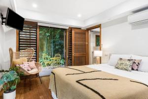 a bedroom with a bed and a balcony at Byron Blisshouse in Byron Bay