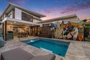 a house with a swimming pool and surfboards on the wall at A Perfect Stay - Byron Sunrise in Byron Bay