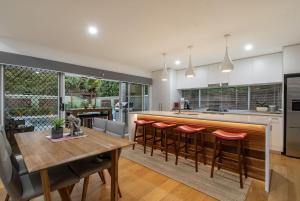 a kitchen with a wooden table and bar with stools at A Perfect Stay - Byron Sunrise in Byron Bay