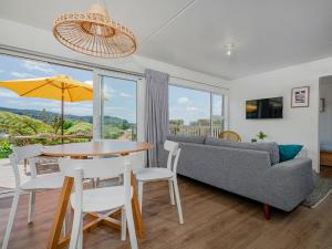 uma sala de estar com uma mesa e um sofá em The Blockhouse - Whangamatā Holiday Home em Whangamata