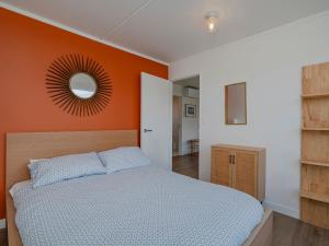 um quarto com uma cama com uma parede laranja em The Blockhouse - Whangamatā Holiday Home em Whangamata