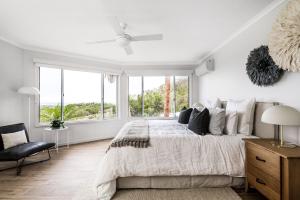 a white bedroom with a large bed and windows at A Perfect Stay - Byron Pacific Vista in Byron Bay