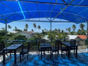 a patio with tables and chairs under a blue umbrella at Siargao By Grace Suites in General Luna