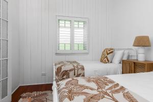a white bedroom with two beds and a window at A Perfect Stay - Cape Cottage in Byron Bay