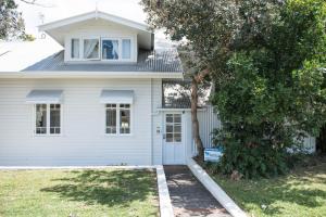 a white house with a tree in front of it at A Perfect Stay - Cactus Rose Villa in Byron Bay