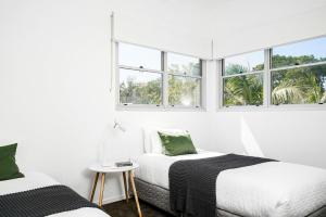 two beds in a white room with windows at A Perfect Stay - Clique 2 in Byron Bay