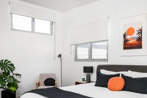 a white bedroom with a bed and two windows at A Perfect Stay - Clique 1 in Byron Bay