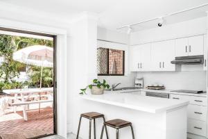 a kitchen with white cabinets and stools in it at A Perfect Stay - Cooinda in Byron Bay
