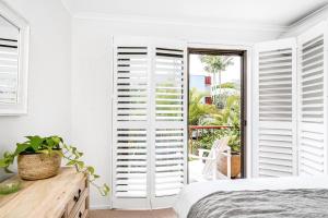 a bedroom with white shutters on the window at A Perfect Stay - Cooinda in Byron Bay
