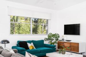 uma sala de estar com um sofá azul e uma televisão em A Perfect Stay - Clique 3 em Byron Bay