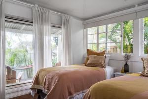 a bedroom with two beds and a large window at A Perfect Stay - Gidgets House and Studio in Byron Bay